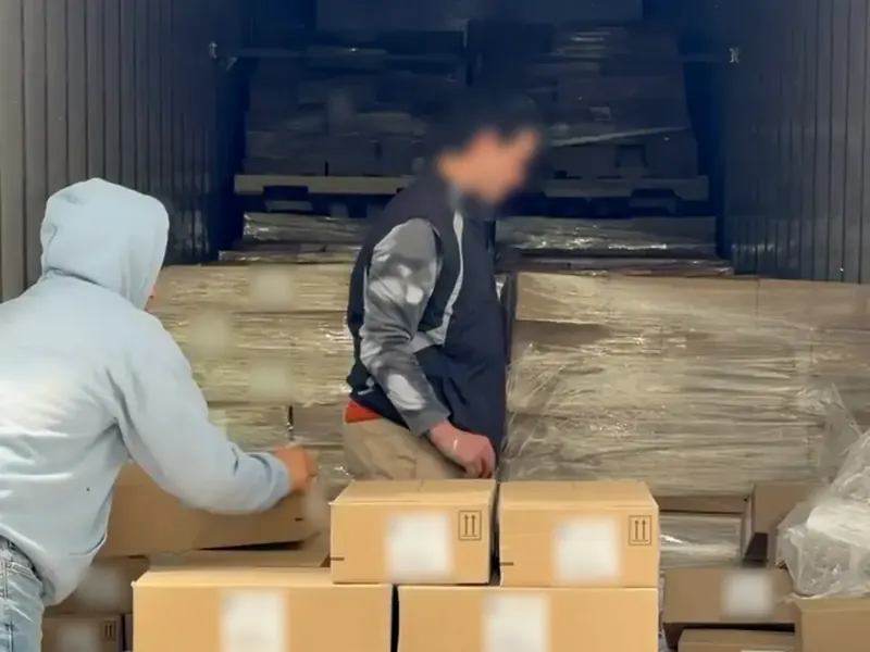 Workers hand-unloading a floor-loaded container onto pallets at the Carlstadt, NJ dock