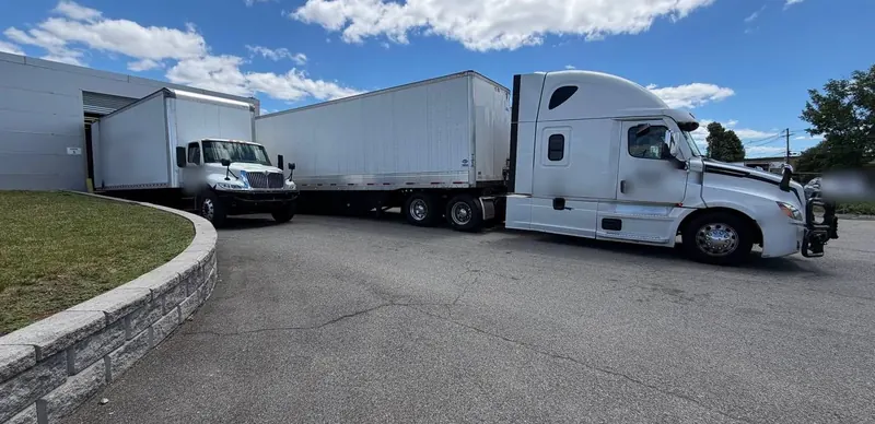 A box truck backed into a dock door and a tractor-trailer in the yard at the Carlstadt, NJ cross-dock