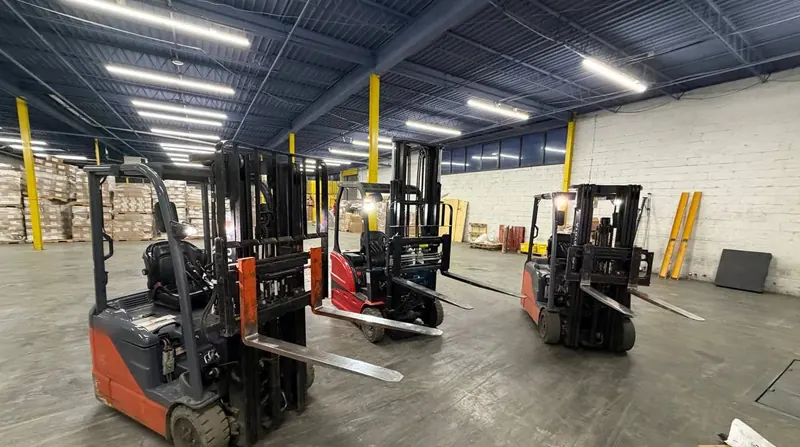 Electric forklifts on the warehouse floor with palletized freight stacked behind them in Carlstadt, NJ